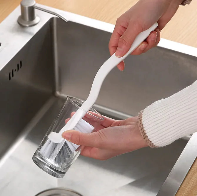 Using the narrow cleaning brush to scrub hard-to-reach areas in the kitchen sink, demonstrating its versatility.
