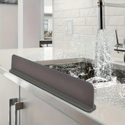 Silicone sink splash guard and flexible water barrier protecting countertop from splashes.
